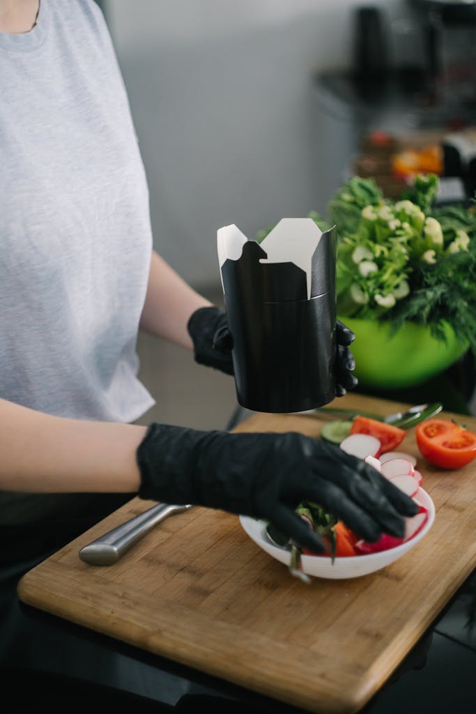 Person preparing a fresh salad meal with vegetables in a modern kitchen setting.