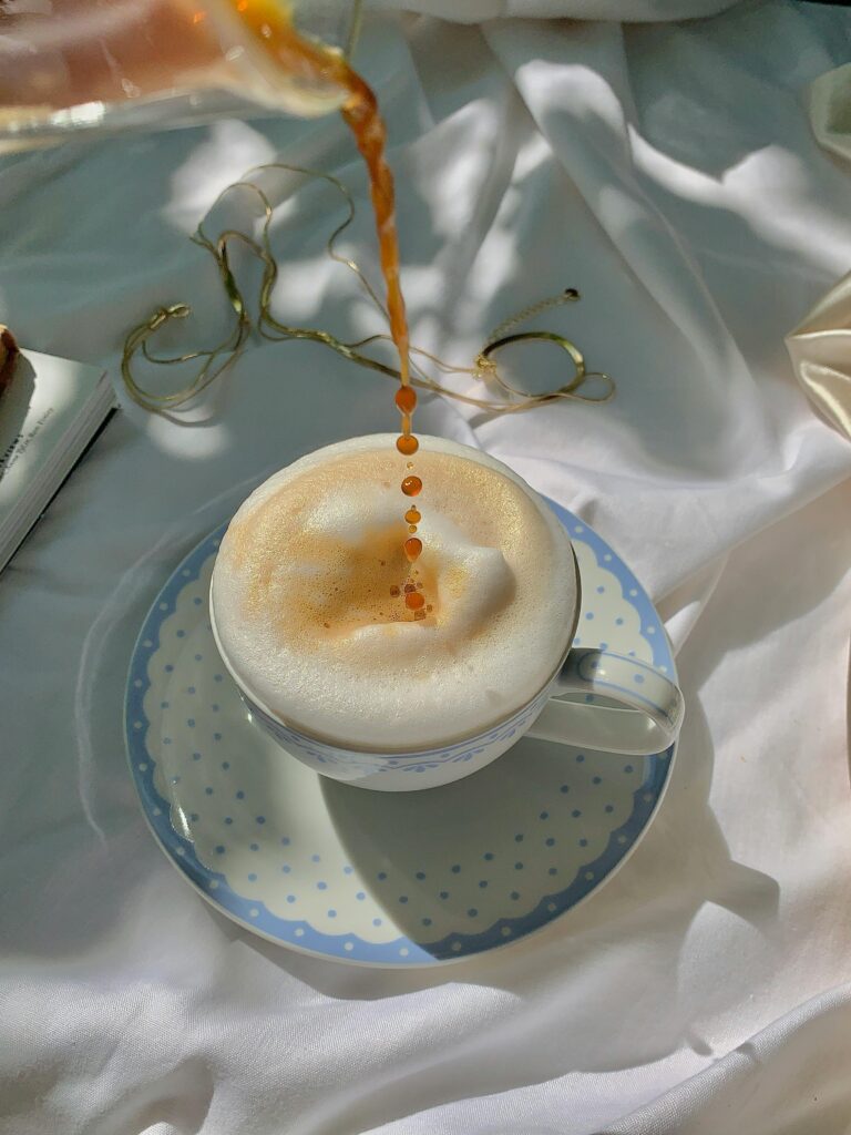 Freshly poured coffee into a frothy cup on a soft white fabric background